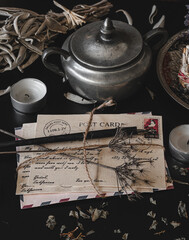 Old vintage looking bundle of postcards hand written in cursive on a dark black messy table. Dried...