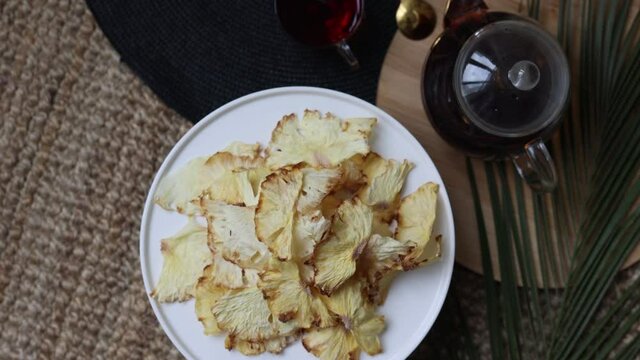Organic dried fruits. Homemade dehydrated fruit chips on a white round tray. The concept of healthy eating. dried pineapple top view. Glass teapot with tea.