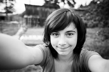 A teengirl takes a selfie in the village. Black and white photo.