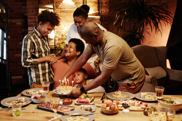 Fototapeta na wymiar Warm toned portrait of happy African-American family celebrating Birthday together indoors at evening