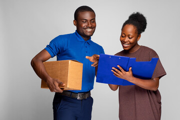 african lady filling details in a manifest to receive a package from a delivery worker