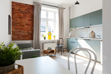 Modern interior of kitchen and dining room with table and chair in industrial loft apartment with bricky wall. Cozy home or hotel.