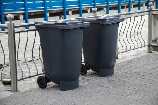 Black indoor waste containers for recycling on sidewalk. Closed and recycle receptacles trash bin outside