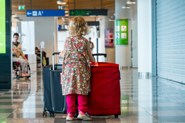 Naklejka na ściany i meble Cute blonde girl with travel luggage at the airport.