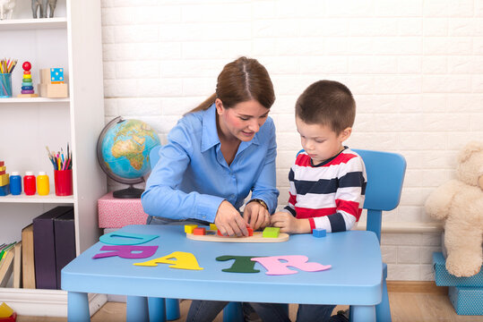 Toddler boy in child occupational therapy session doing sensory playful exercises with her therapist.