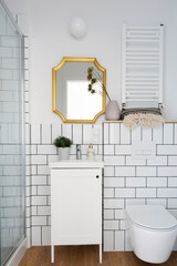 Bathroom with tiles, cabinet with sink and gold mirror on the wall. Interior of small luxurious...