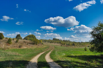 Autumn landscape with field road and the cloudy sky