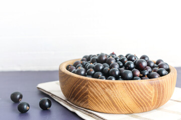 Fresh black currant in wooden bowl on dark table