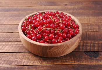 Fresh red currant in wooden bowl on wood table.