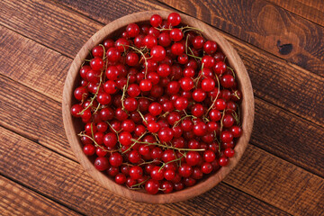 Fresh red currant in wooden bowl on wood table.