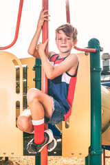 Happy little boy climbing up or sliding down a playground pole