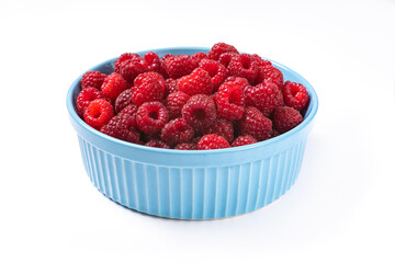 Red raspberry berry in plate on wooden table.