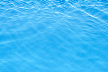 Fototapeta na wymiar The surface of light on the blue transparent swimming pool water. Trendy abstract wavy background. Water waves in sunlight banner.