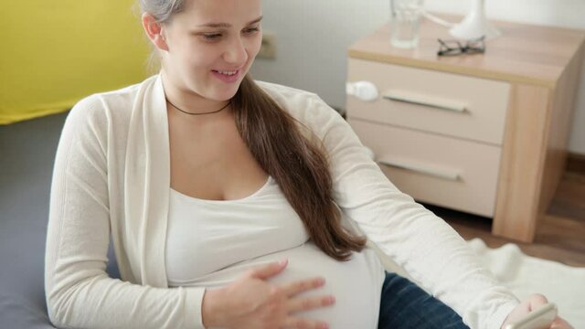 Cute Pregnant Woman Make Video Call Smartphone Online Consultation With Doctor By Mobile Phone. Young Ledy In Pregnancy Have Fun Spend Time On Floor At Home. Motherhood, Medicine Health Care Concept