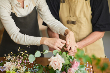 Close up of two florists arraigning flower compositions in cozy workshop, copy space