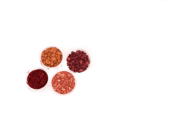 Creative photo of cosmetic swatches. Broken eye shadows in bronze and pink colours on a white background 