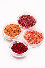 Creative photo of cosmetic swatches. Broken eye shadows in bronze and pink colours on a white background 