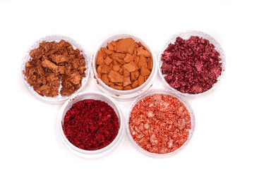 Creative photo of cosmetic swatches. Broken eye shadows in bronze and pink colours on a white background 