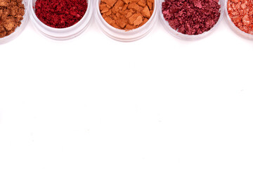 Creative photo of cosmetic swatches. Broken eye shadows in bronze and pink colours on a white background 