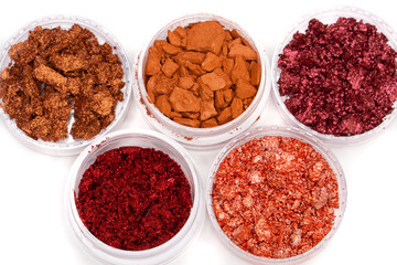 Creative photo of cosmetic swatches. Broken eye shadows in bronze and pink colours on a white background 