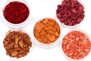 Creative photo of cosmetic swatches. Broken eye shadows in bronze and pink colours on a white background 