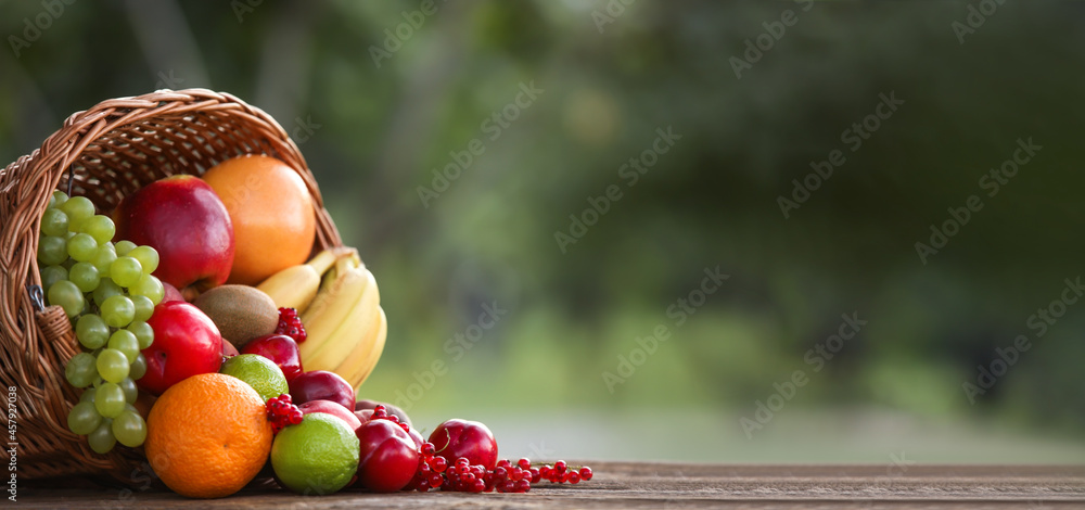 Wall mural wicker basket with fresh fruits on table with space for text