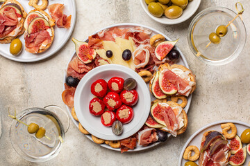 Top view of appetizers and vermouth cocktail. Bruschetta, cold cuts of prosciutto, cheese, tuna fish stuffed mini bell peppers, taralli, olives, grapes and figs.