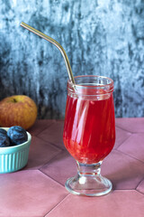 red drink in a glass glass with a metal drinking tube