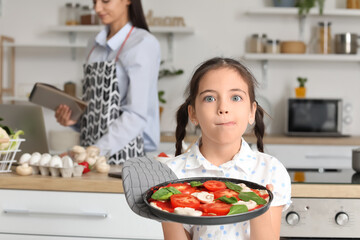 Little girl cooking pizza in kitchen at home