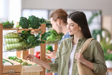 Obraz premium Young woman choosing vegetables in market