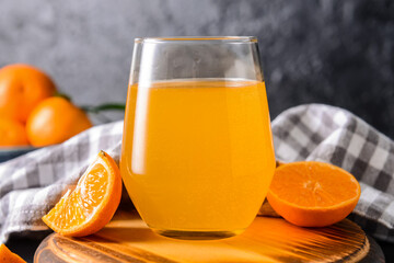 Glass with tasty orange juice on dark background