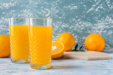 Glasses with tasty orange juice on color background