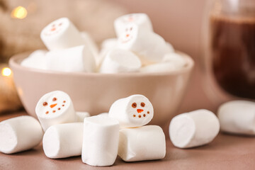 Bowl with snowmen made of soft marshmallows on color background