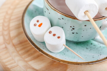 Snowmen made of soft marshmallows and cup of hot chocolate on table, closeup