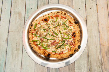 Chicken pizza with peppers and red onion with lots of mozzarella cheese on a steel plate