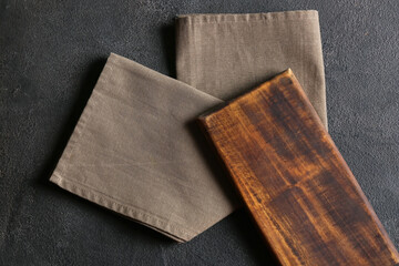 Wooden board and stylish napkin on dark background