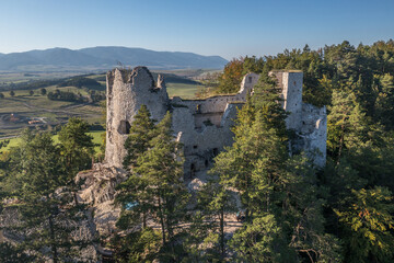 Fototapeta na wymiar Aerial view of medieval Blatnica Gothic hilltop castle ruin above the village in a lush green forest area with towers and restoration work in Slovakia