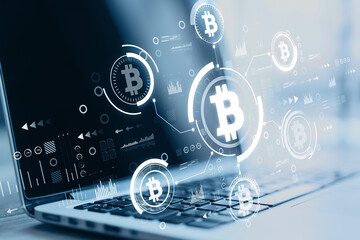 Close up of laptop at blurry desktop with creative glowing blue bitcoin interface on dark background. Finance, technology, cryptocurrency and exchange concept. Double exposure.
