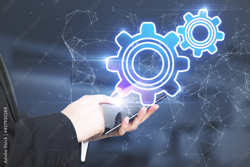 Aufkleber Close up of businessman hand pointing at tablet device with abstract glowing gear wheels on blurry background with connections. Digital engineering and industry concept.
