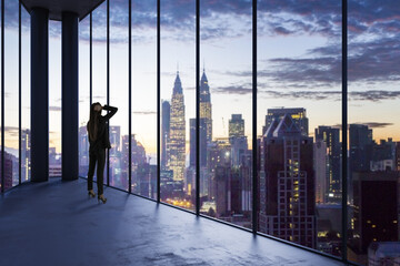 Business woman in empty office looking out of panoramic window with bright city downtown view. Future, tomorrow, perspective and career concept.