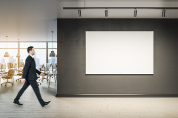 Fototapeta premium Businessman walking in modern office interior with blank wall, mock up poster and window with city view.