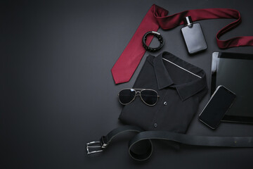 Stylish male clothes with accessories, mobile phone and tablet computer on dark background