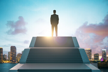Fototapeta na wymiar Back view of young european business man standing on top of stairs on bright city background with sky view. Leadership, growth and success concept.