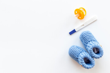 Pregnancy test and blue baby boy booties. Morherhood and pregnancy concept