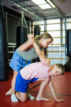 Sportive preteen boy and girl practicing in pair self-protection in sport class at school