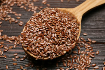 Spoon with flax seeds on wooden background, closeup
