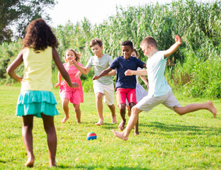 Positive kids running on field and playing football together.