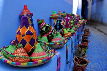 Colorful Moroccan handicrafts on wall at a blue street in Chefchaouen, Morocco.