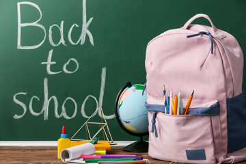 Backpack and stationery against blackboard with text BACK TO SCHOOL