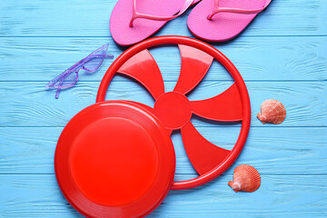 Frisbee disks, sunglasses and flip-flops on color wooden background